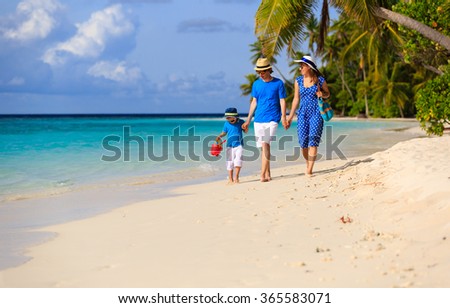 family with child walking on tropical beach