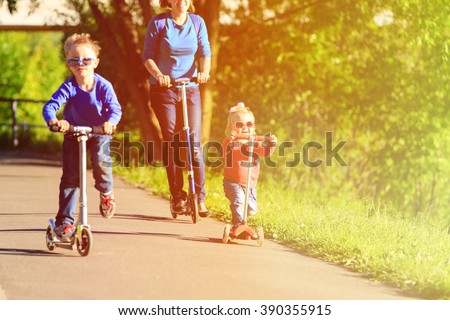 mother with kids riding scooters in summer