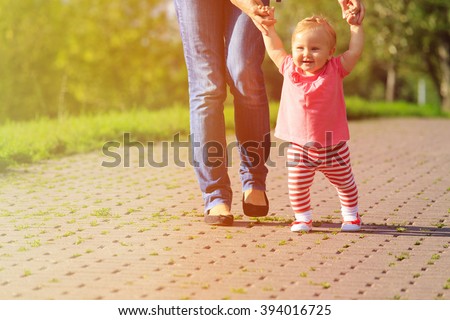 first steps of little girl in summer park