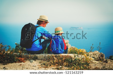 family travel -father and son hiking with backpack in mountains