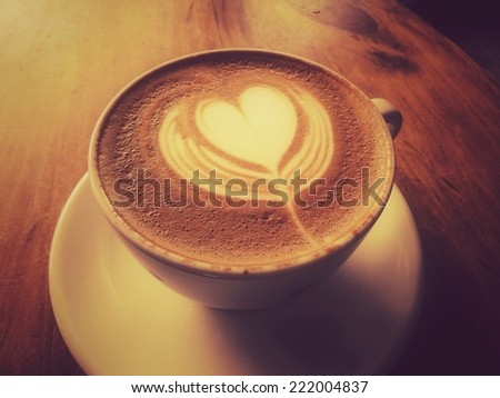 Latte or cappuccino coffee on wooden desk with retro filter effect or Instagram filter