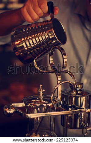 hand of barista  pouring dripping water for coffee,making coffee with Belgian Royal style Syphon Coffee Maker in retro filter effect or instagram filter
