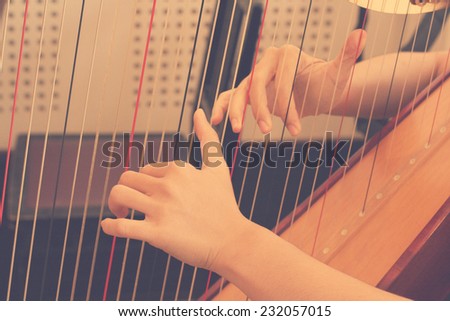 Closeup of a woman playing the harp in rehearsal practice room with retro filter effect lighting or instagram filter