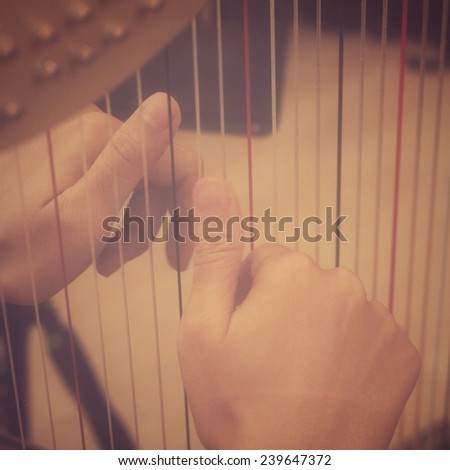 Women's hand playing harp in retro filter effect or instagram filter