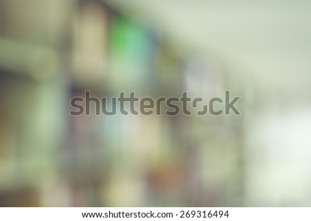 Blurred books on the shelf and the light from windows in public library. Blurred effect. Background for your pictures