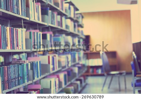 Blurred library with books on the shelf, chairs table and the light from windows in public library. selective focus Blurred effect. Background for your pictures