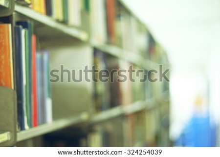 Blurred library with books on the shelf, chairs table and the light from windows in public library. selective focus Blurred effect. Background for your pictures