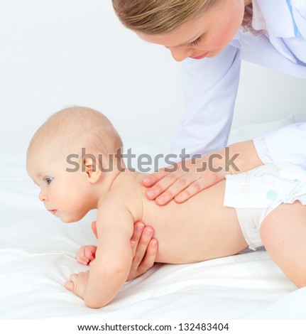 Baby massage. Young Medical Doctor Woman massaging/ touching child back. Cute small kid lying on his tummy.
