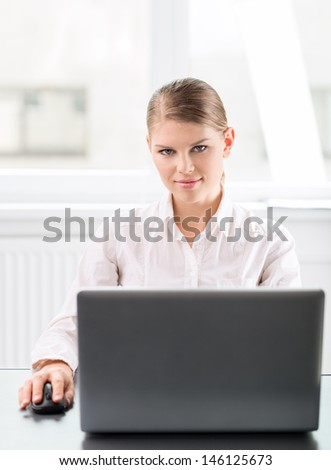 Financial career woman with laptop at the workplace. Confident successful business lady sitting at her desk in the office.