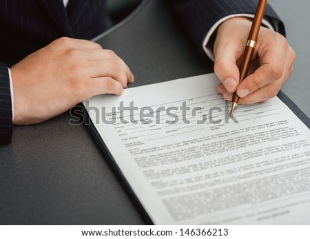 Shoot of financial director\'s hands signing business contract at the desk in his office.