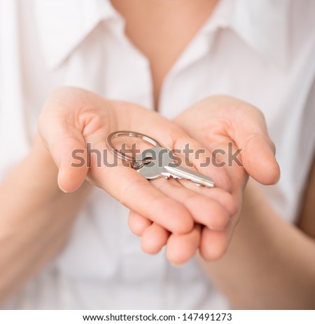 Real estate consultant woman holding a key of a new apartment in hands. Close-up of female house seller\'s hands with key.
