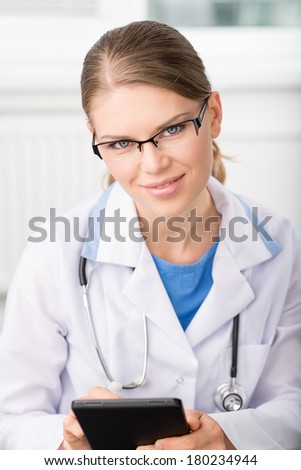 Pretty woman physician in eyeglasses with i pad in hospital.