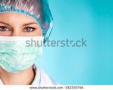 Close-up portrait of woman doctor in surgical mask and cap over blue background with copy space for text.