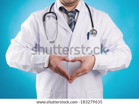 Male doctor cardiologist wearing professional uniform showing heart shape. Heart aid and treatment concept.