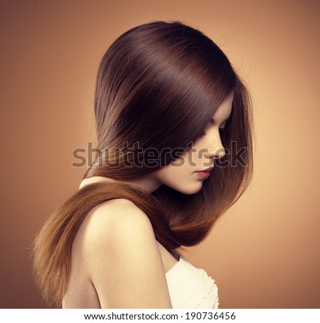 Close-up portrait of young model with glossy straight brown hair. Hair care and coloring.