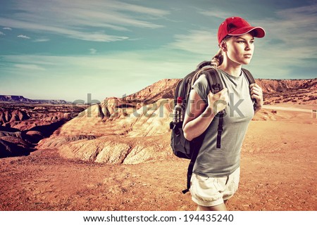 Hiking woman. Young female tourist camping in desert on sunset. Picture of beautiful desert landscape and blue sky in summer.