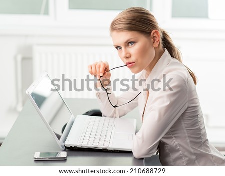 Uncertain business woman seeking for problem solving. Portrait of thinking female analyst sitting in front of her notebook in the office.