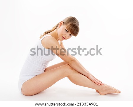 Beautiful slim woman model touching her waxed legs, isolated over white background. Body and skin care.
