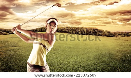 Young female golf player swinging with golf club outdoors. Woman in sportswear playing golf on green field over beautiful landscape background.