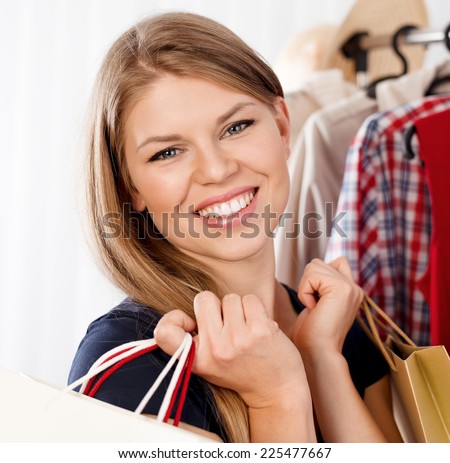 Close up of fashionable woman buyer with shopping bags. Young pretty Caucasian female purchasing clothes in small boutique.