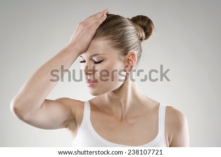 Close-up portrait of young stressed woman touching her forehead in pain. Memory loss and headache concept.