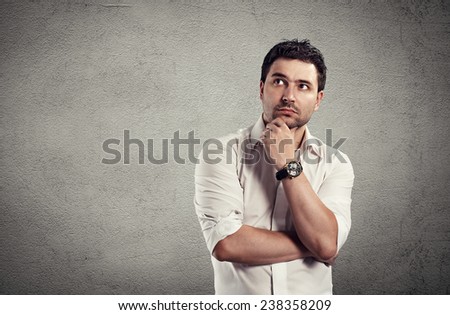 Portrait of handsome young business man having creative idea. Conceptual shoot of Caucasian brunette standing at grey wall.