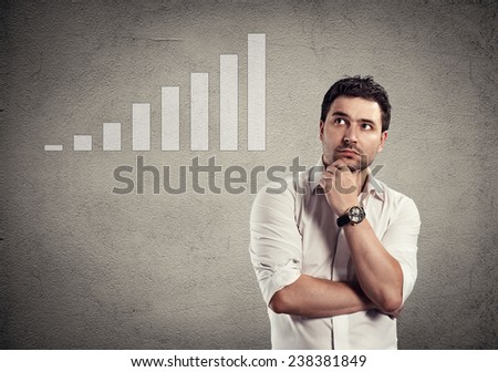 Young business person thinking of sales increase, development and improvement. Handsome Caucasian male looking at diagram of growth.