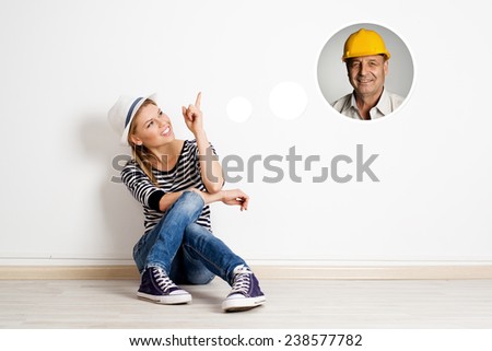 Young female new flat owner dreaming to call professional repairman. Pretty cheerful woman sitting on the floor in empty room having idea of apartment design.
