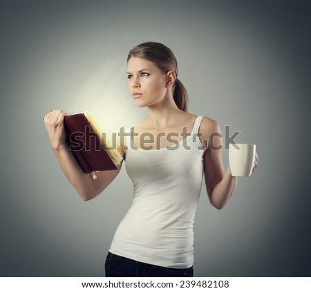 Knowledge light. Conceptual shoot of young woman getting information and ideas from the book holding cup of aromatic tea.