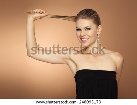 Studio portrait of happy smiling woman model holding her long tail. Healthy hair ends concept.