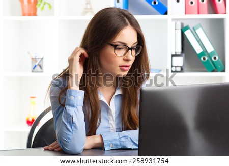 Portrait of female business consultant working at her laptop. Young concentrated woman economist checking data via internet.