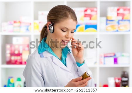 Portrait of woman doctor pharmacist in headset speaking in microphone. Young friendly female chemist working in drug store.