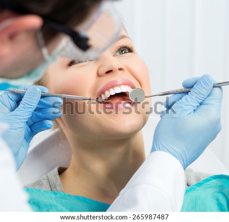 Dental health. Male hygienist examining patient teeth on caries. Young woman showing her teeth to doctor.