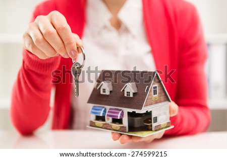 Closeup of female house agent holding keyring of rented house. Real estate contract. Shallow depth of field.