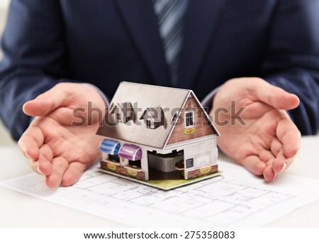 Male house agent showing family residence model to customers. Real estate agreement concept. Shallow depth of field.