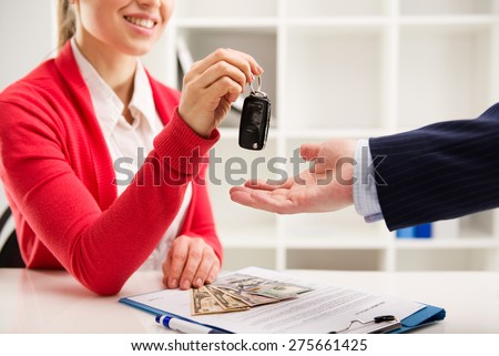 Rental contract. Transport purchase. Woman automotive dealer offering car key to buyer. Shallow depth of field.