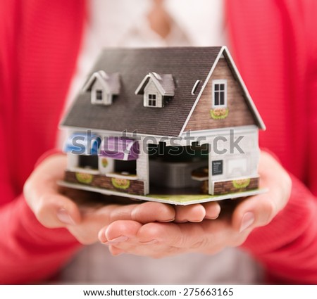 Closeup of woman mortgage consultant holding house model. Concept of new home sale or rent. Shallow depth of field.