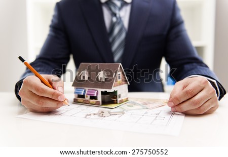 Closeup of male architect drawing heating system plan of customer house in the office. Real estate value and cost concept.  Shallow depth of field.
