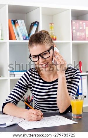 Young casual female tax consultant talking on phone sitting at the desk. Home job concept.