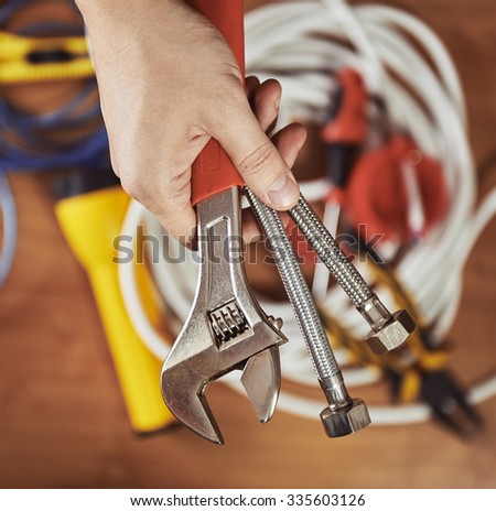 Plumber hand holding instruments. Male builder ready to install faucet in a kitchen.