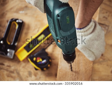Building master with drilling machine. Professional carpenter working with wood and building tools in house.