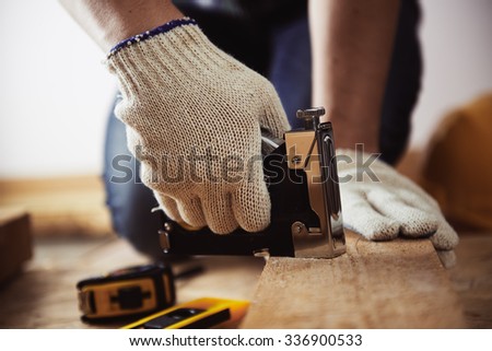 Close-up of craftsman hands working with construction instruments on the floor in his workshop .