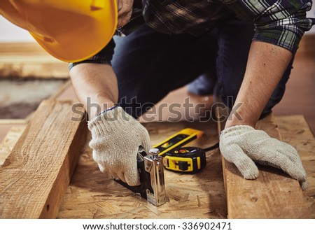 Young man builder in workwear repairing wooden furniture in a house. Concept of renovation and woodwork.