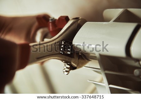 Plumbing repair service. Professional installer with spanner checking pipes.