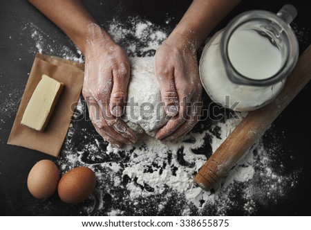 Woman hands kneading dough on the black board with eggs, milk, butter and flour. Healthy breakfast preparation concept.