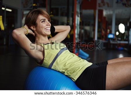 Beautiful smiling girl doing press exercise on fit ball in aerobics class. Sport, active lifestyle and health.