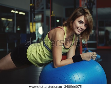 Pretty smiling woman training pilates on fit ball in fitness class. Sport, physiotherapy and lifestyle.