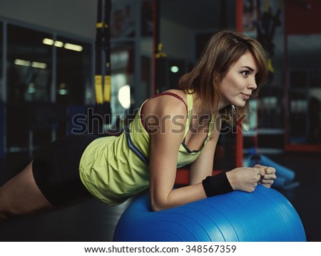 Young sporty female doing core exercise on the ball in yoga class. Concept of weight loss and body improvement.