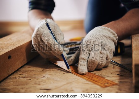 Woodworker with lumber. Professional builder evaluating size of workbench with pencil and ruler.