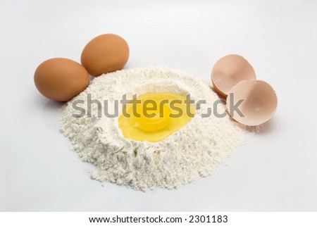 An egg in some flour preparing for baking with eggs and egg shells in the sides